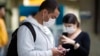 Pasajeros usando mascarillas como precaución contra el contagio del nuevo coronavirus usan sus teléfonos en el Aeropuerto Internacional de Sao Paulo, Brasil.